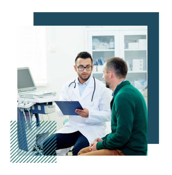 Two men are sitting on stools in a medical office. One is wearing a lab coat and stethoscope. He is holding a clipboard and appears to be mid-sentence. Another man is sitting next to him and listening.